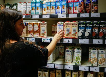 Una mujer mira bebidas verdes en un supermercado de Madrid.