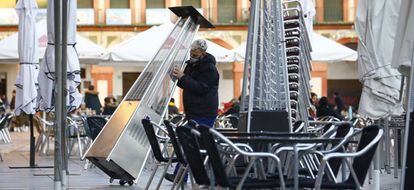 Un trabajador recoge el mobiliario de la terraza de un restaurante en el centro de Córdoba hoy lunes cuando han entrado en vigor las nuevas restricciones en Andalucía