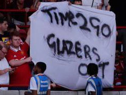 Un aficionado del Manchester United sostiene una pancarta contra la familia Glazer. AFP