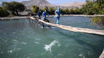 Trabajadores de salud cruzan el río Camaná para vacunar a ancianos contra COVID-19, en Arequipa, sur de Perú.