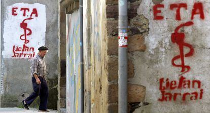 Un hombre pasa al lado de un grafiti con el logo de ETA.