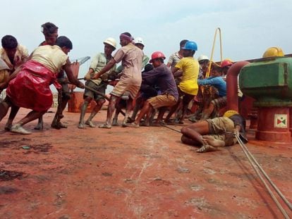 Un grupo de hombres trabajan descalzos, sin guantes ni material de protección en el desguace de un barco en Bangladés.