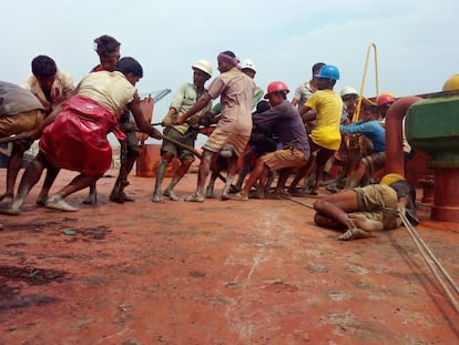 Un grupo de hombres trabajan descalzos, sin guantes ni material de protección en el desguace de un barco en Bangladés.