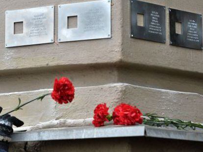 Una mujer pone flores bajo una placa en Mosc&uacute;.