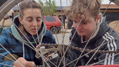 Dos colaboradoras del Taller de Bicis del Vecindario, reparan la cadena de una bicicleta, en Córdoba (Argentina).