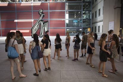 Un grupo de jóvenes turistas esperan para comprar su entrada del Museo Reina Sofía junto a la escultura 'Brushstroke' de Roy Lichtenstein.