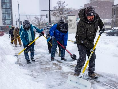 Trabajadores retiran nieve de las banquetas en Des Moines, Iowa, el 12 de enero 2024.