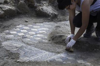 Una restauradora limpia uno de los mosaicos del yacimiento de Écija.