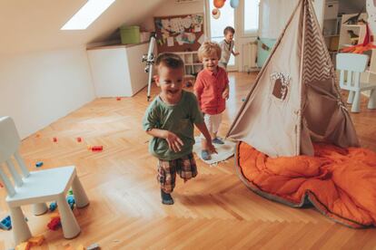 Tres niños corren y juegan en una casa.