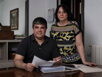 Cristina Calderón y Joan Manel Argüelles, en el salón de su casa, en Barcelona, con la documentación de su adopción.
