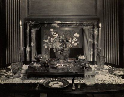 Diseño de mesa de Elsie de Wolfe aparecido en 'Vogue' en 1924 con candelabros de cristal veneciano, pecera-florero, pieza central de cristal marrón y coral tapete de encaje de Battenberg y platos de postre Copeland de 1870 decorados por Bough. |
