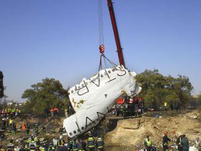 Una grúa levanta parte del fuselaje de la aeronave.