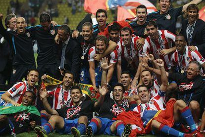 Los jugadores del Atlético posan en el césped con el trofeo, que suejeta Forlán y tapan Agüero y Jurado con sus brazos
