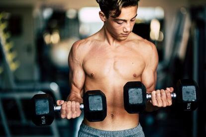 Un adolescente ejercita sus músculos en el gimnasio.