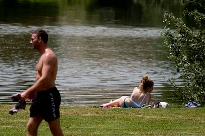 Una chica toma el sol y un chico pasea sin camiseta junto al río durante el primer día de ola de calor del 22 de mayo en Sevilla.