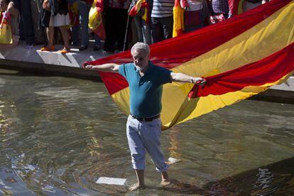 Un hombre sostiene una bandera mientras camina por la fuente de Colón.