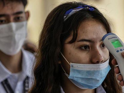 Personal de seguridad toma la temperatura a los estudiantes que entran a una universidad de Manila (Filipinas).