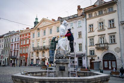 Dos operarios protegen una de las estatuas del centro de Lviv para evitar que sufran daños ante un ataque ruso, en el octavo día desde el inicio de la guerra en Ucrania.
