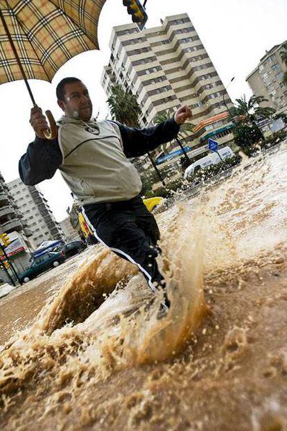 Un hombre cruza una avenida  anegada en el centro de Málaga.