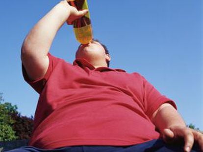 Un hombre obeso bebe de una botella.