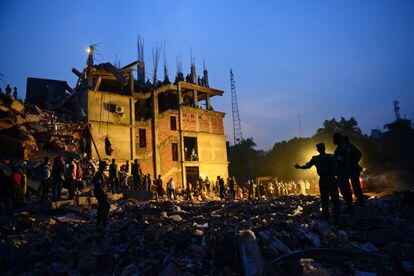 Personal militar y voluntarios trabajan en las laboras de rescate de supervivientes en el edificio Rana Plaza de ocho plantas situado en la ciudad de Savar, a 30 kilómetros de Dacca (Bangladesh). Los servicios de rescate han logrado sacar a 50 personas con vida del edificio derrumbado.