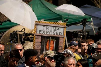 Un manifestante sujeta un cartel con la imagen de Donald Trump, a las puertas del tribunal penal de Manhattan que ha procesado al exmandatario estadounidense. 