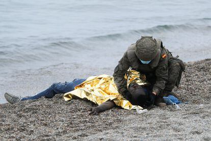 Un soldado del Ejército ayuda a un inmigrante que ha conseguido atravesar uno de los espigones de Ceuta, este martes. La llegada de personas a nado y a pie fue constante durante todo el lunes y martes en la misma playa donde se han desplegado tanques.