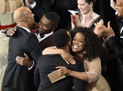Oprah Winfrey (d) y el actor David Oyelowo (2i) saludan efusivamente a los músicos Common (i) y John Legend (de espaldas) antes de subir al escenario a recoger su Oscar por la mejor canción, 'Glory' de 'Selma'.