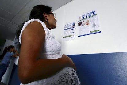 Mujer embarazada lee un anuncio sobre el virus del zika.