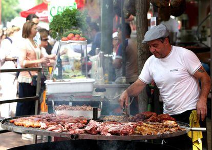 Un cocinero prepara carnes a la brasa en un bar de la feria de San Isidro.