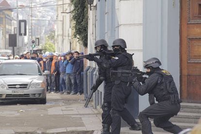 Fuerzas de seguridad protegen unas instalaciones policiales, después de que los estudiantes lanzaran piedras al edificio.