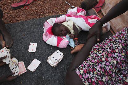 Una madre juega a las cartas mientras su bebé descansa en el campo de refugiados de la misión UNMISS de la ONU en Rumbek, Sudán del Sur. 19 de marzo de 2014.