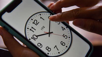 Una persona cambia la hora en el reloj de su teléfono celular.
