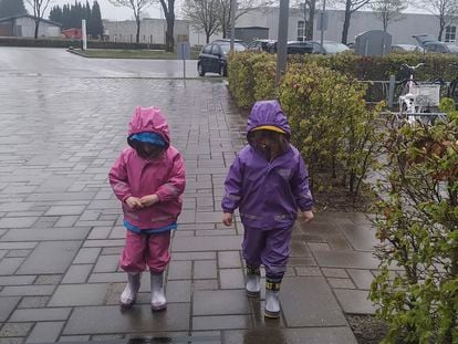 Maia y Milena, vestidas con el traje de lluvia y las botas de agua, vuelven al colegio en Dinamarca.