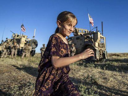 Una niña corre por un campo cerca de varios vehículos militares en la ciudad siria de al-Malikiyah, cerca de la frontera turca, el 7 de junio de 2020.