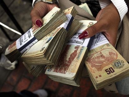 Una mujer sostiene fajos con billetes de soles peruanos, en un centro de cambio en Lima.