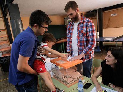 Un ni&ntilde;o mete en la urna el voto de su padre en un colegio de Madrid.