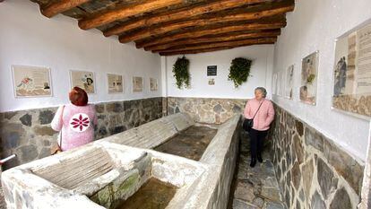 Dos mujeres visitan los poemas creados en Mecina Bombarrón y expuestos en los antiguos lavaderos del pueblo.