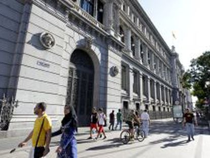 Varios transeúntes caminan por la madrileña calle de Alcalá, junto al edificio del Banco de España.