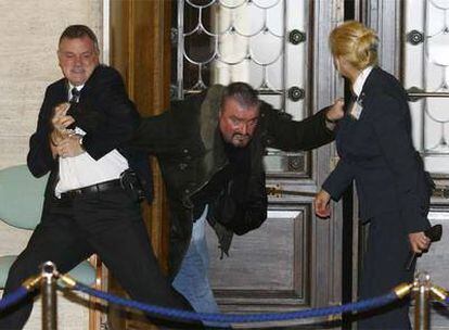 Dos agentes de seguridad reducen a Stone a la entrada de la Asamblea de Irlanda del Norte.