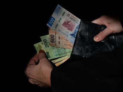 Una persona saca billetes de su cartera en México.