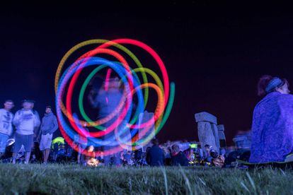 Un hombre hace girar barras luminosas en la noche del 21 de junio durante la celebración del solsticio de verano en Stonehenge.
