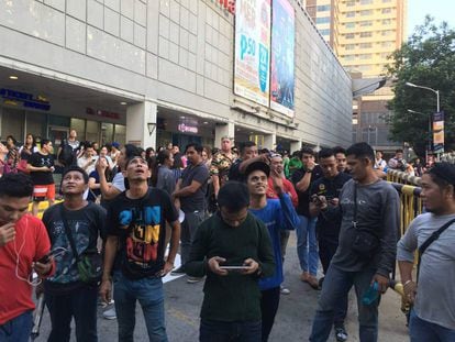 Varios ciudadanos evacuados de un centro comercial en Manila tras el terremoto. 