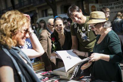 Unos ciudadanos posan sonriendo ante una parada de libros.