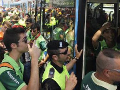 Decenas de jóvenes tratan de subir a un autobús de la EMT en Aluche para llegar al aeródromo de Cuatro Vientos.