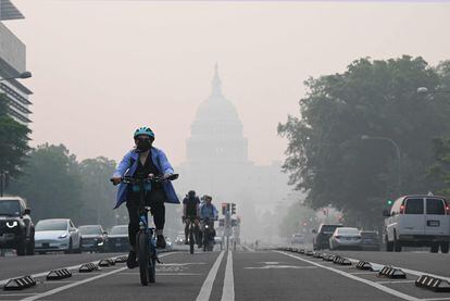 Un ciclista viaja bajo un manto de neblina que oscurece parcialmente el Capitolio de los EE UU