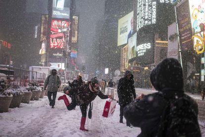Varios turistas se divierten bajo la nieve en Times Square, en Nueva York.