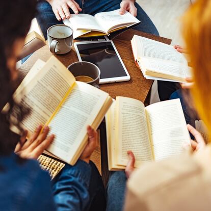 Diverse group of friends discussing a book in library.