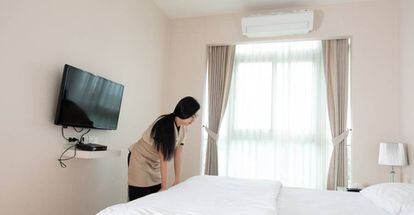 Una trabajadora limpia una habitación de hotel. 