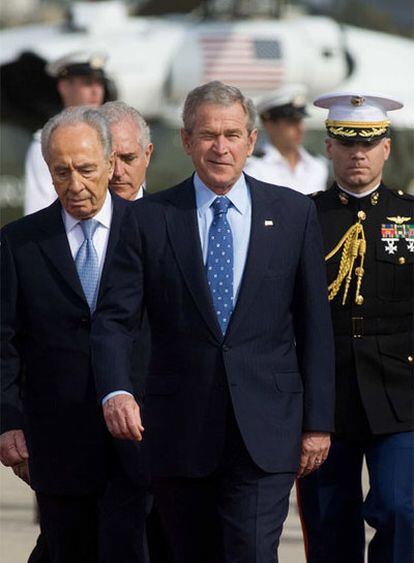 Bush, seguido de Simon Peres, a la izquierda, guiña un ojo mientras camina por el aeropuerto de Tel Aviv.